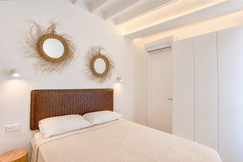 Dormitorio con armarios empotrados y vigas vistas en vivienda reformada en Palma
