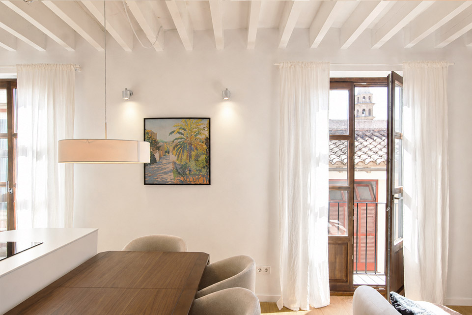 Comedor con balcón y vigas de madera en vivienda reformada del casco antiguo de Palma
